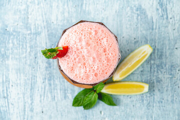 Strawberry and lemon milkshake or smoothie on blue stone background
