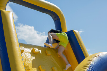 A man climbs an inflatable slide. An obstacle course for entertainment.