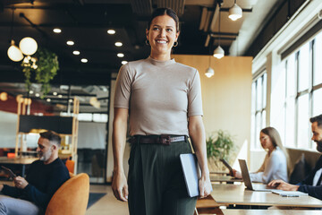 Happy businesswoman standing in a co-working space