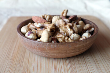A mixture of nuts in a wooden bowl on a wooden board. Dried nuts.