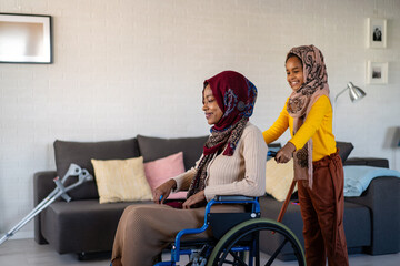 Caring muslim child helping parent in wheelchair with disability to live happy life