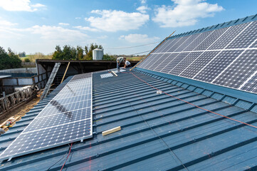 Energie renouvelable. Pose de panneaux photovoltaiques sur le toit d'un batiment agricole ancien