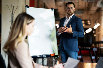 Businessman present his idea to working team. Young handsome man presenting businessplan