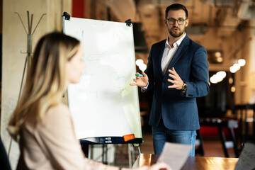 Businessman present his idea to working team. Young handsome man presenting businessplan
