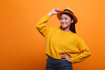 Portrait of happy joyful positive asian woman laughing heartily while wearing yellow sweatshirt. Cheerful charming woman smiling wide with confidence while wearing colorful vivid blouse.