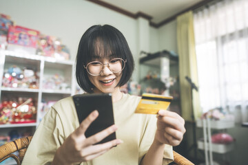 Young adult asian woman using smartphone and credit card make transaction via digital application