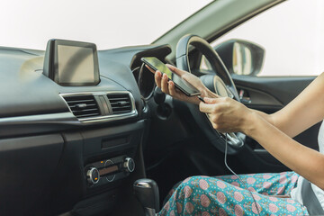 Woman driver charging her smart phone in the car.