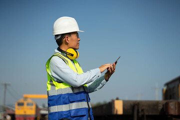 The engineer in a helmet and uniform,Working with tablet for plan,Engineers working on railway train statation.