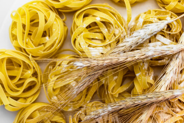 Nest pasta from durum wheat sprinkled with flour on a white background. Close-up. Spikelets of wheat. Home cooking. Pasta background.