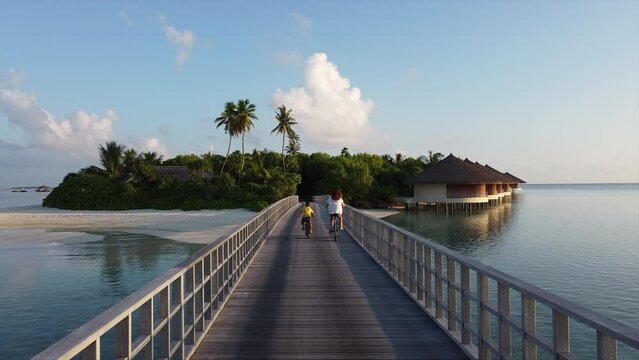 Mother and son riding their bikes throw a bridge on a Maldive Islands