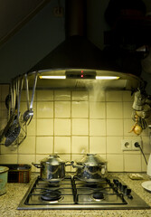 Meal preparation in the evening: pans on gas stove in kitchen by lamplight