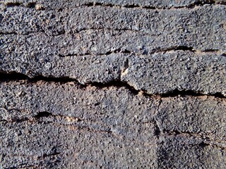 Grayish-brown stone surface with horizontal cracks, texture, wallpaper, background.
