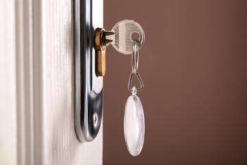 Key with fob in door lock, closeup. Space for text