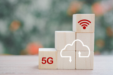 stack of wooden cube block with wifi , 5G, and cloud storage icon on wood table and blurred nature background for technology, networking concept