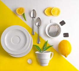 On a yellow-white background, two cups for tea, saucers, tea bags, lemon, spoons.