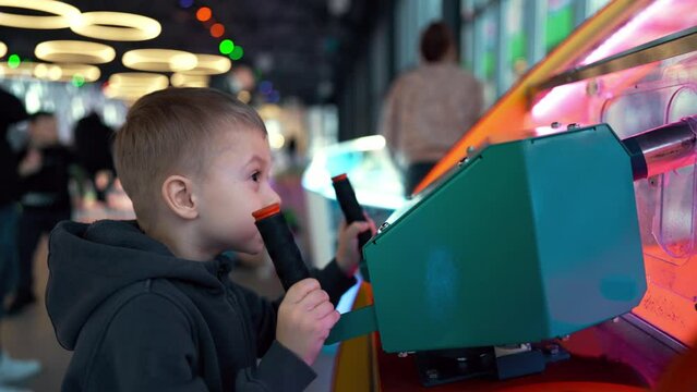 Boy playing on the kids game machine at an amusement park. Child playing on the kids game machine.