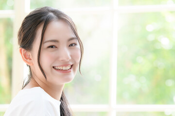 笑顔が美しい日本人女性　緑の背景ボケあり