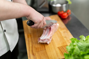 Chef cutting the meat on a wooden board