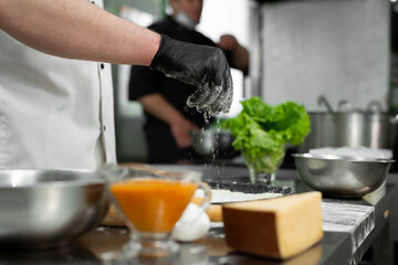 Preparation of the dough for pizza. Close-up of the cook's hand sprinkling the dough with flour