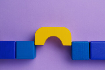 Bridge made of colorful blocks on violet background, flat lay. Connection, relationships and deal concept
