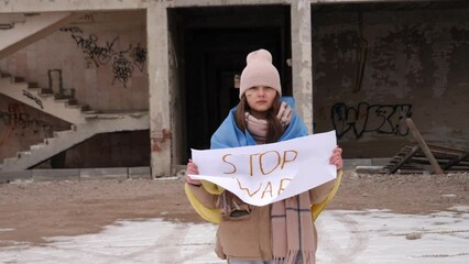 Upset Ukrainian poor girl kid protesting war conflict raises banner with inscription massage text Stop War. Crisis, peace, stop aggression, child against Russian war