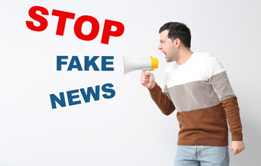 Screaming young man with megaphone and text STOP FAKE NEWS on light background