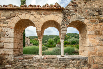 View through the well preserved Renaissance arched windows of the garden of the Abbey of Sant Antimo. Tuscany, Italy