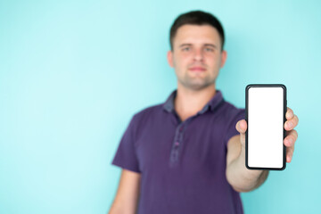 Mobile application. Happy man. Digital technology. Smiling defocused guy showing smartphone blank screen posing isolated blue copy space.