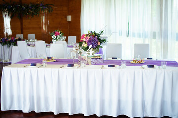 Festive textile decor in the restaurant with floral arrangements on the table near the plates