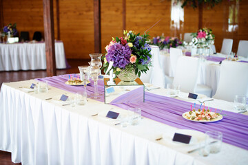 Festive textile decor in the restaurant with floral arrangements on the table near the plates