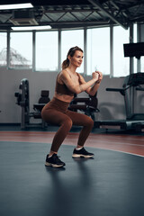 Naklejka na ściany i meble Pretty woman working out in a gym with small weights. Adult lady with beautiful shaped body.