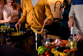 Group of friends preparing vegetarian meal in a kitchen at home.