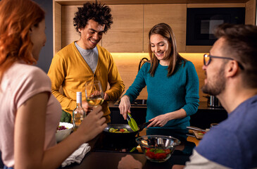 Group of friends preparing vegetarian meal in a kitchen at home.