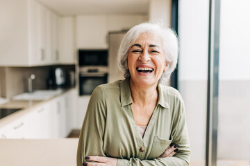 Cheerful elderly woman laughing happily inside her home