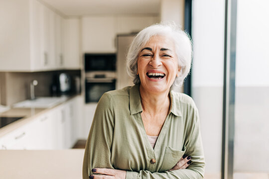 Cheerful elderly woman laughing happily inside her home