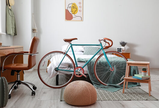Interior of light room with bed, bicycle and step stool