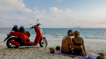 Scooter road trip. Lovely couple on red motorbike in white clothes on sand beach. Just married...