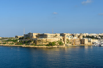 Overlooking the Grand Harbour from Kalkara, Malta is Villa Bighi which was a British Royal Naval Hospital Bighi from 1830 to 1970. On the right is the cot lift that was used to bring up patients from  - obrazy, fototapety, plakaty