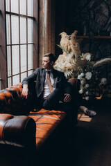 Naklejka premium Morning of a stylish groom, man, in a black suit and tie, his preparations at the hotel, in a photo studio, fastening buttons and jacket, portraits