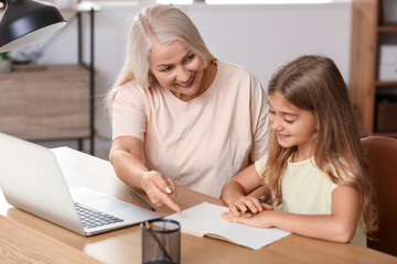 Fototapeta premium Little girl with her grandmother doing lessons at home