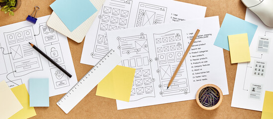 Web design concept banner. User experience designer desk with numerous website wireframe sketches...
