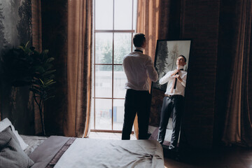 Morning of a stylish groom, man, in a black suit and tie, his preparations at the hotel, in a photo...