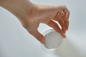 A woman changes a ceiling energy saving light bulb with LED light lamp in a home living room. Work at height self, diy
