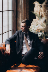 Morning of a stylish groom, man, in a black suit and tie, his preparations at the hotel, in a photo...