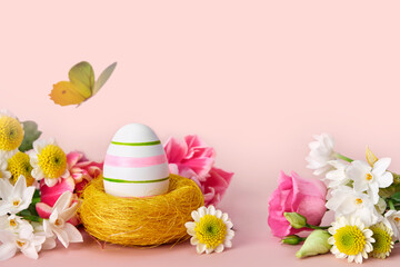 Easter creative composition. Spring flowers, Easter egg and butterflies on a pink background. Easter card