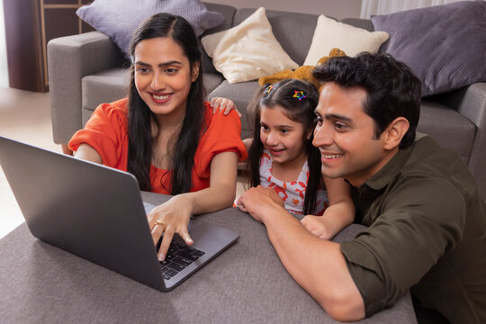 Parent using laptop with their girl child at home