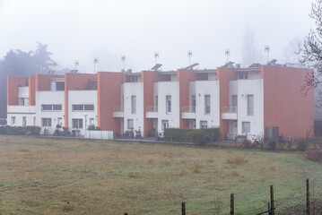 Exterior of a row modern terraced houses in the countryside on a foggy winter morning