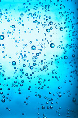 Clear water with bubbles on blue background, closeup