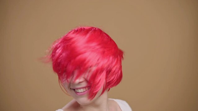 Smiling young red haired woman waving hair, slow motion.