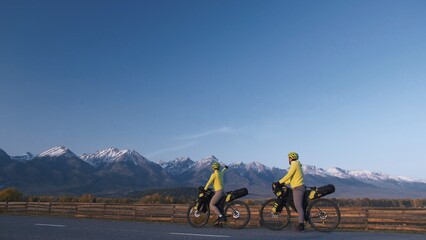 The man and woman travel on mixed terrain cycle touring with bikepacking. The couple journey with...